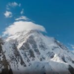 Величественная заснеженная вершина горы К2 (Чогори) с ледниками и облаком над пиком на фоне синего неба
